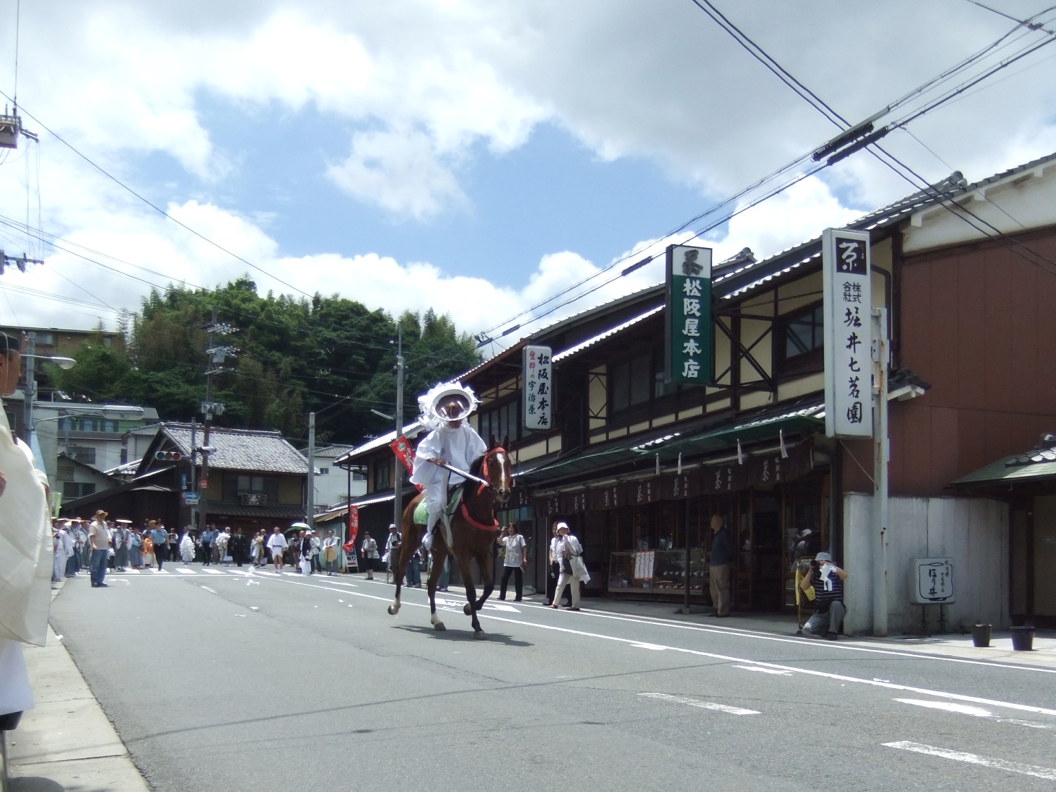 大幣を担ぐ幣差（力者）を馬に乗った神人（御方）が追いかける様子の画像